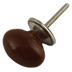 Könnte beinhalten: Ein brauner Keramik-Schrankknopf mit einem silbernen Metallsockel und einer Schraube.