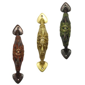 May include: Three ornate brass door handles with a face design. The handles are in gold, green, and red.