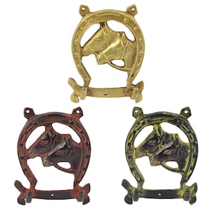 Könnte beinhalten: Drei Metallhaken in Form eines Hufeisens mit Pferdeköpfen. Die Haken sind in Gold, Rot und Grün.