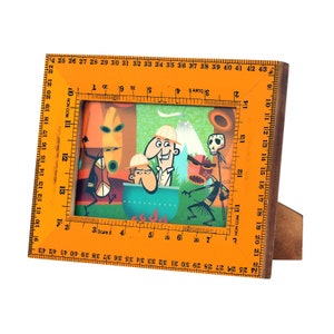 Op de afbeelding: Een houten fotolijst met een oranje liniaalrand. De lijst heeft een kleurrijke illustratie van cartoonfiguren met een tropisch thema. De tekst "3 Scale 8" is op de liniaal gedrukt.