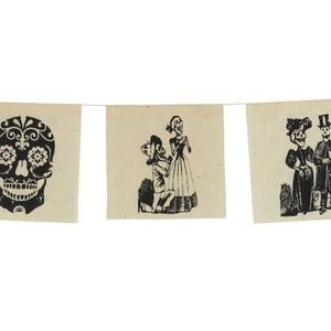 May include: A decorative banner featuring three off-white rectangular fabric panels suspended on a thin string. Each panel displays a black ink illustration: a detailed sugar skull, a skeleton kneeling before a standing skeleton, and two skeletons.