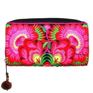 Könnte beinhalten: Eine schwarze Reißverschluss-Geldbörse mit einem floralen Stickmuster. Die Blumen sind rot, pink und gelb mit grünen Blättern auf schwarzem Hintergrund.