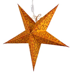May include: A large, gold paper star with red and gold patterned details. The star is hanging from a white string.