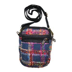 May include: A small, colorful crossbody bag with a woven plaid pattern in shades of blue, red, and pink. The bag has a black zipper and strap, and gold-colored metal hardware. The bag is approximately 6 inches tall.