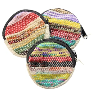 May include: Three round coin purses with zipper closures. Each purse is made of woven fabric with colourful stripes in shades of red, yellow, green, blue, and purple. The purses are made of recycled materials.