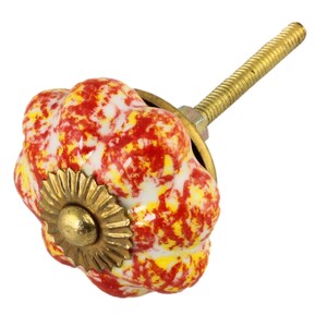 May include: Red and yellow ceramic knob with a gold metal base and a screw. The knob has a textured, bumpy surface.