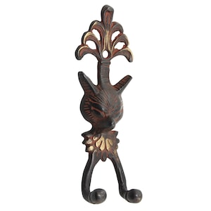 Könnte beinhalten: Ein dekorativer Metall-Wandhaken mit einem katzenartigen Gesicht und einem stilisierten floralen Design. Der Haken ist hauptsächlich dunkelbraun mit roten und goldenen Akzenten. Er hat zwei abgerundete untere Haken.