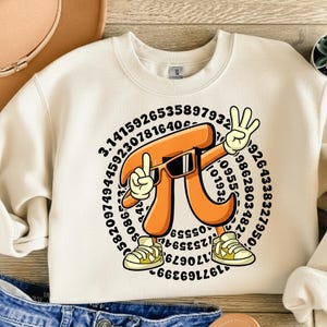 Può includere: Felpa color crema con un simbolo Pi a cartoni animati che indossa occhiali da sole e scarpe da ginnastica, che fa il segno della pace. Il simbolo Pi è circondato da numeri. La felpa è abbinata a jeans blu e un cappello marrone.