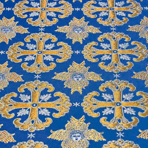 May include: Blue fabric with a repeating pattern of gold crosses and winged cherubs. The fabric has a textured, woven look.