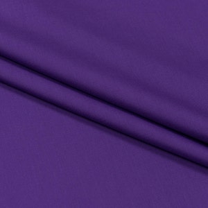 May include: A close-up of a smooth, purple fabric with a subtle texture. The fabric is folded in a way that creates a soft, flowing drape.