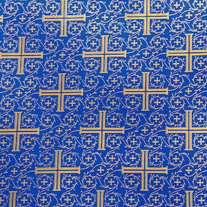 May include: A blue fabric with a repeating pattern of gold crosses and floral designs.