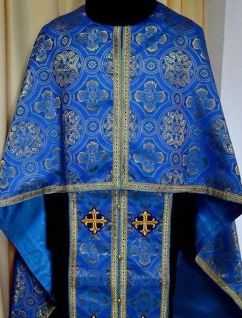 Puede incluir: Una vestimenta lit&uacute;rgica azul con bordados dorados y un dise&ntilde;o estampado. La vestimenta tiene un cuello y una t&uacute;nica larga y fluida.