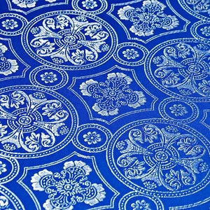 Puede incluir: Primer plano de una tela azul con un patr&oacute;n blanco intrincado y repetitivo. El patr&oacute;n presenta un dise&ntilde;o circular con una flor central y cuatro hojas circundantes.