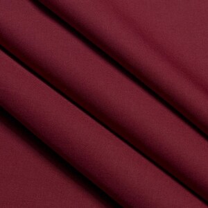 May include: A close-up of a smooth, burgundy fabric with soft folds and wrinkles.