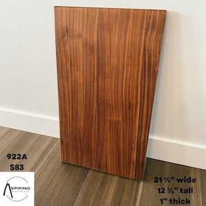 Puede incluir: Una tabla de cortar rectangular grande de madera de color marrón oscuro con un patrón de veta de madera. La tabla mide 21 1/2 pulgadas de ancho, 12 1/2 pulgadas de alto y 1 pulgada de grosor. El texto "922A $83" es visible en la esquina inferior izquierda de la imagen.
