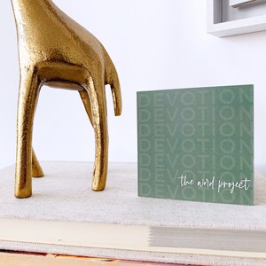 May include: A green card with the word "devotion" repeated multiple times in a white font. The text "the word project" is written in white at the bottom of the card.