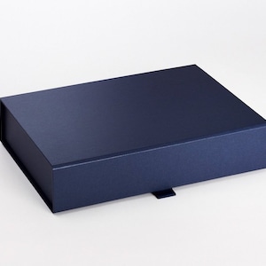 May include: A navy blue rectangular gift box with a magnetic closure. The box has a matte finish and a small tab on the front for easy opening. The box is empty and sits on a white background.