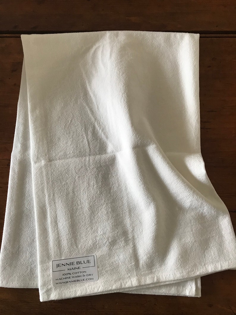 Pode incluir: Toalha de cozinha branca com um r&oacute;tulo que diz "Jennie Blue Maine 100% Algod&atilde;o Lavar na m&aacute;quina e secar www.jennieblue.com"