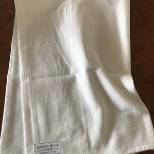 Peut inclure: Serviette de cuisine blanche avec une &eacute;tiquette indiquant "Jennie Blue Maine 100% Coton Lavage et s&eacute;chage en machine www.jennieblue.com"