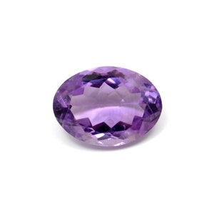 May include: A large, oval-shaped amethyst gemstone with a purple hue. The gemstone is faceted and has a high polish.