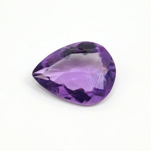 May include: A pear-shaped amethyst gemstone with a deep purple hue. The gemstone is faceted and has a high degree of clarity.