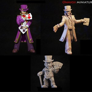 Op de afbeelding: Drie beschilderde beeldjes van mensen die hoge hoeden dragen en speelkaarten vasthouden. De beeldjes staan in verschillende poses en zijn in verschillende kleuren geschilderd. De beeldjes staan op een zwarte achtergrond.