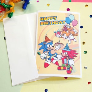 sonic birthday card with sonic, tails, and knuckles. Card says happy birthday on front. White envelope included