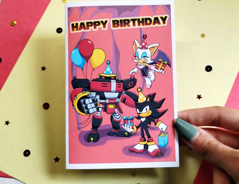 Sonic birthday card being held in hand that says Happy Birthday at the top in a colorful Sonic themed font. Image has Team Dark (Shadow, Rouge, and Omega) holding gifts.