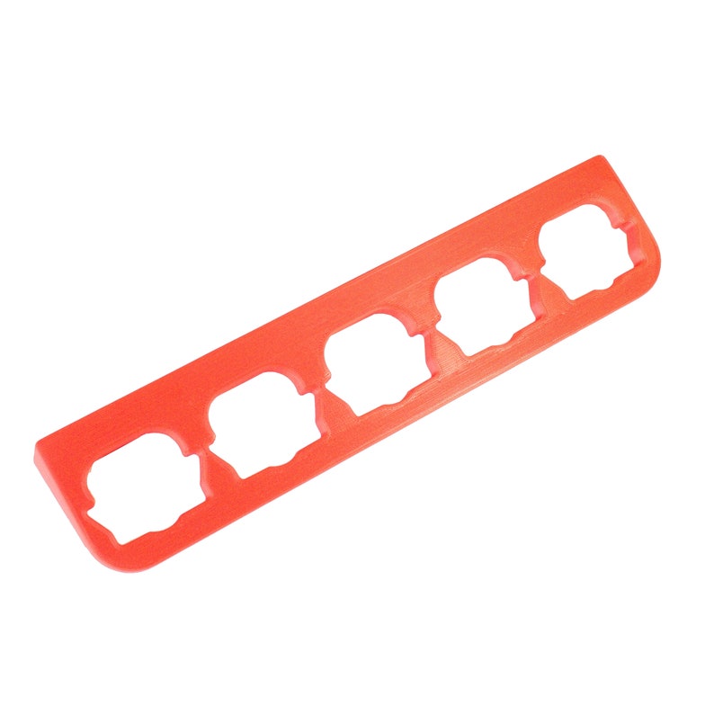Puede incluir: Una herramienta de pl&aacute;stico roja con cinco recortes en forma de flores. La herramienta se utiliza para crear formas de flores en fondant u otros materiales comestibles.