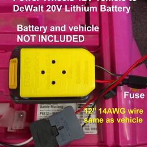 May include: A yellow and black adapter with the text "PW-D20F Fused Adapter" and "PowerDock Made in USA". The adapter is connected to a gray connector with the text "PW 125 USA+". The adapter is connected to a red and black wire. The text "12" 14AWG wire same as vehicle" is visible. The background is pink.