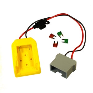 May include: A yellow battery charger with a gray connector and a red and black wire. There are four spare fuses in the image, one red, one green, and two clear.
