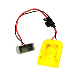 May include: A yellow battery charger with a black connector and red and black wires. The charger has two slots for batteries.