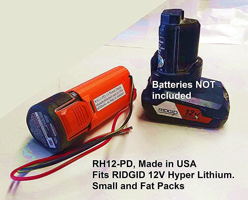 Puede incluir: Primer plano de dos bater&iacute;as de herramientas el&eacute;ctricas de color naranja y azul. La bater&iacute;a naranja est&aacute; etiquetada con "RH12-PD-14 Power Dock MadeByMitchell.com in USA MSBurko on ebay & Amazon". La bater&iacute;a azul est&aacute; etiquetada con "RIDGID 12V High Capacity" y tiene el texto "Batteries NOT included". El texto "RH12-PD, Made in USA Fits RIDGID 12V Hyper Lithium. Small and Fat Packs" est&aacute; escrito debajo de las bater&iacute;as.