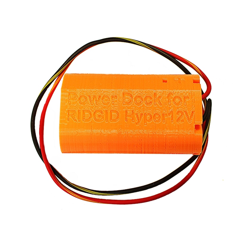 Puede incluir: Base de alimentaci&oacute;n naranja impresa en 3D para una bater&iacute;a RIDGID Hyper 12V. La base tiene tres cables conectados: rojo, negro y amarillo.
