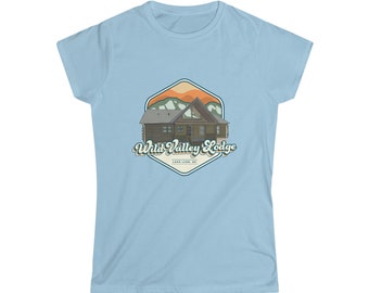 Könnte beinhalten: Hellblaues T-Shirt mit einem Retro-Grafikmotiv eines Ferienhauses und dem Text "Wild Valley Lodge". Das Ferienhaus ist braun mit einem grünen Dach, vor dem Hintergrund orangefarbener und grüner Berge. Darunter steht der Text "Lake Lure, NC".
