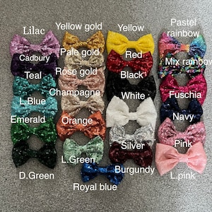 Op de afbeelding: Een verzameling van 20 pailletten strikken in verschillende kleuren, waaronder lila, geel goud, geel, pastel regenboog, cadbury, teal, roze goud, zwart, champagne, wit, fuchsia, lichtblauw, smaragd, oranje, marine, zilver, roze, lichtgroen, bordeauxrood en koninklijk blauw.