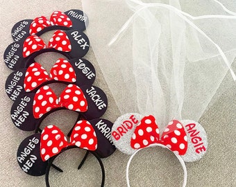 Puede incluir: Conjunto de nueve diademas negras con lazos de lunares rojos y blancos y el texto "Angie's Hen" en cada diadema. Una diadema tiene el texto "Bride" y purpurina plateada.