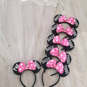 Op de afbeelding: Set van zes zwarte hoofdbanden met roze stippenboogjes en de tekst "Bride Tribe" in zilveren glitter. E&eacute;n hoofdband heeft de tekst "The Bride" in plaats van "Bride Tribe".