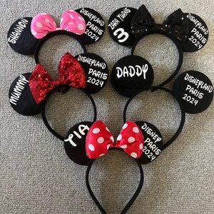 May include: Set of six black mouse ears headbands with white text and colorful bows. The text on the headbands reads "Mummy", "Shannon", "Daddy", "Tara Turns 3", "Yia", and "Disneyland Paris 2024".