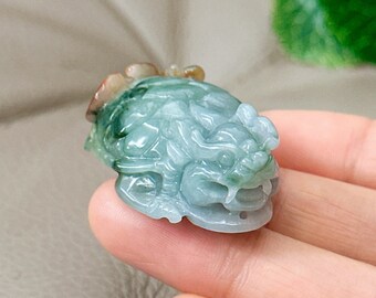 May include: A jade green dragon pendant with intricate details. The pendant is carved from jade and has a light green color with brown accents.