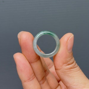 May include: A jade ring with a light green color. The ring is smooth and polished.