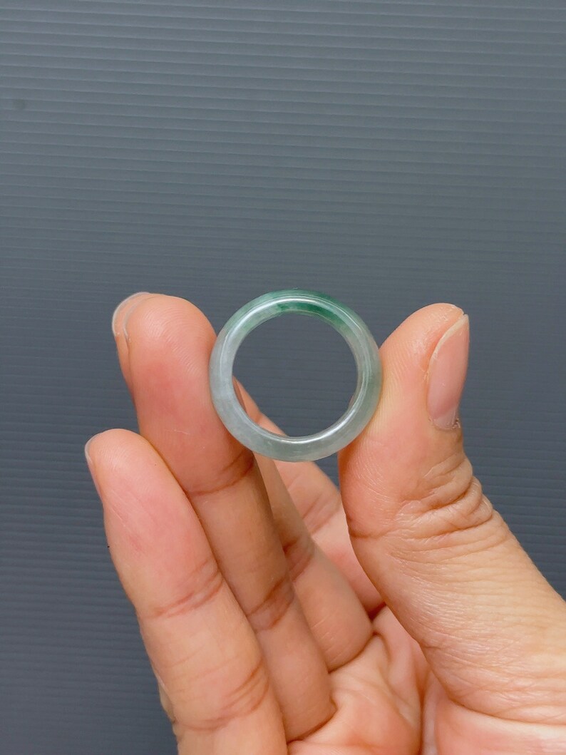 May include: A jade ring with a light green color. The ring is smooth and polished.