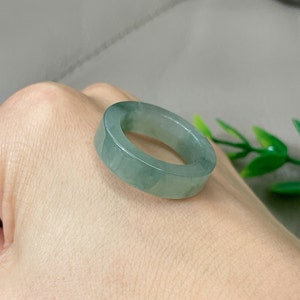 May include: A jade ring with a light green color. The ring is simple and has a smooth, polished finish.