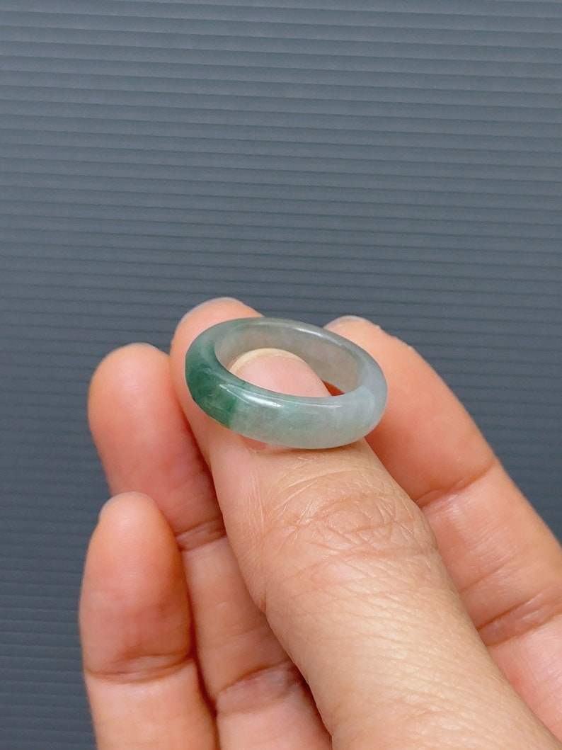 May include: A jade ring with a light green band and a darker green band.