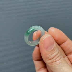 May include: A jade ring with a light green color. The ring is smooth and polished.
