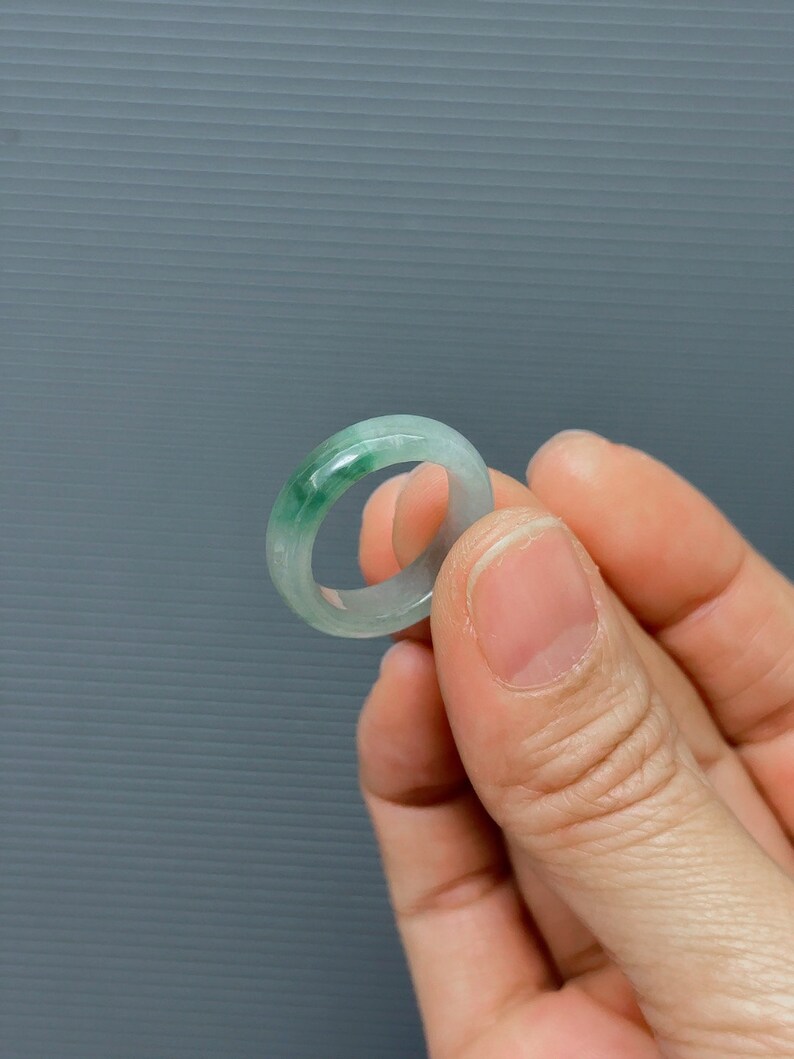 May include: A jade ring with a light green color. The ring is smooth and polished.