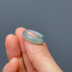 May include: A jade green ring with a smooth, polished finish. The ring is a simple band with a slightly rounded shape.