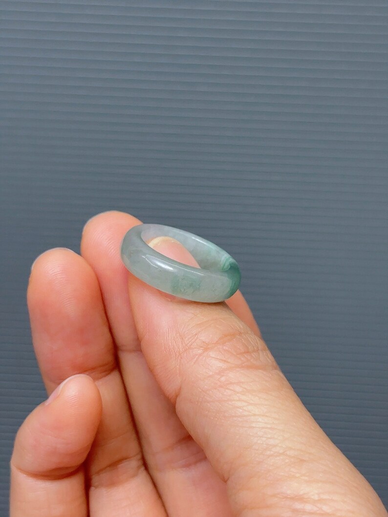 May include: A jade green ring with a smooth, polished finish. The ring is a simple band with a slightly rounded shape.
