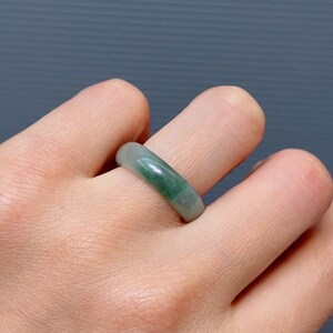 May include: A green jade ring worn on a finger.