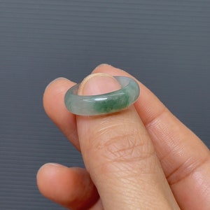 May include: A jade green ring with a smooth, polished finish. The ring is a simple band with a slightly rounded shape.